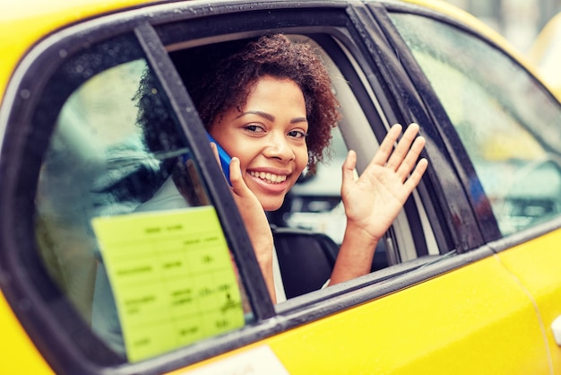 concept-voyage-affaires-transport-voyage-geste-personnes-jeune-femme-afro-americaine-souriante-appelant-smartphone-agitant-main-taxi-dans-rue-ville-normal
